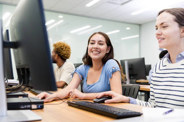 Two female college students work on their computer assignment.